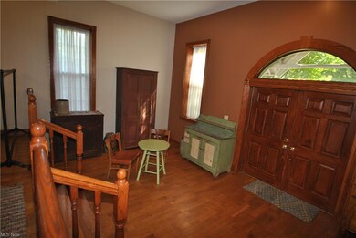The living room has wood floors, tall windows, soa