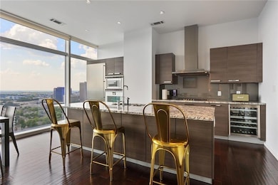 Kitchen with beverage cooler, wall chimney range hood, modern cabinets, a breakfast bar, and a wall of windows