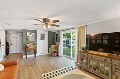 Living room featuring a ceiling fan, a textured ce
