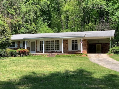 Ranch-style house with driveway, a front lawn, a carport, and brick siding
