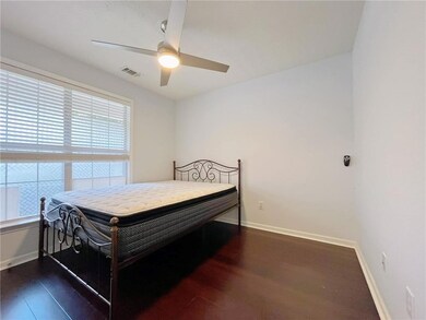Bedroom with a ceiling fan, wood finished floors, baseboards, and visible vents