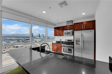 Kitchen with stainless steel appliances, a view of city, dark stone counters, recessed lighting, and a wall of windows