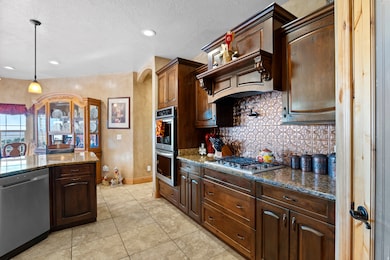 Kitchen featuring stainless steel appliances, dark brown cabinets, dark stone countertops, tasteful backsplash, and decorative light fixtures