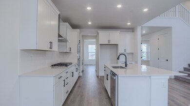 Kitchen featuring white cabinetry, light wood-style floors, a kitchen island with sink, light stone countertops, and recessed lighting