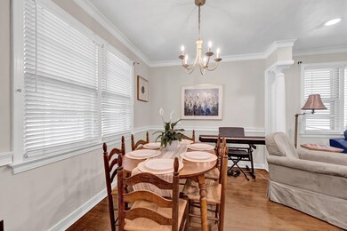 Dining area featuring ornamental molding, a chandelier, wood finished floors, ornate columns, and baseboards