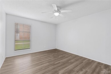 Empty room with baseboards, a textured ceiling, and wood finished floors