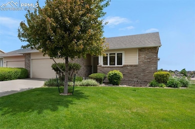 View of front of property with brick siding, driveway, an attached garage, and a front lawn