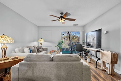 Living room featuring ceiling fan and wood-type fl