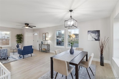 Dining room featuring light wood-type flooring, ceiling fan, and a chandelier