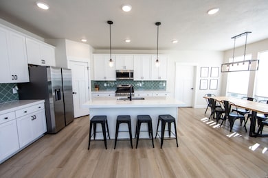 Kitchen with hanging light fixtures, appliances with stainless steel finishes, a breakfast bar area, white cabinetry, and recessed lighting