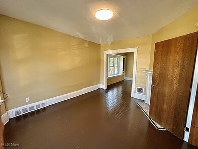 Empty room with dark wood-type flooring and baseboards