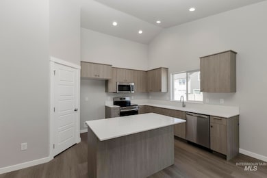 Kitchen featuring modern cabinets, stainless steel appliances, dark wood-style flooring, high vaulted ceiling, and a kitchen island