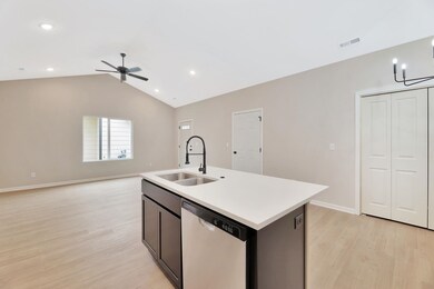 Kitchen with vaulted ceiling, a kitchen island with sink, open floor plan, stainless steel dishwasher, and light wood-style flooring