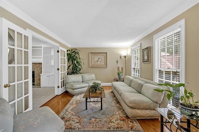 Living room featuring crown molding, wood finished floors, french doors, and baseboards