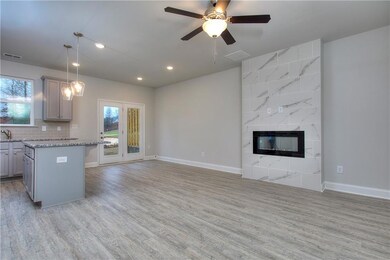 Kitchen with gray cabinets, hanging light fixtures, light stone countertops, a breakfast bar, and light wood-style floors