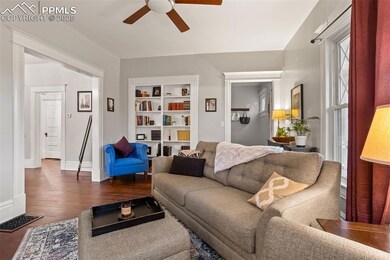 Living room featuring dark wood-style floors, built in features, visible vents, a ceiling fan, and baseboards