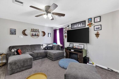 Carpeted living room featuring ceiling fan