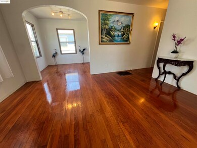 Corridor with arched walkways, wood finished floors, and track lighting