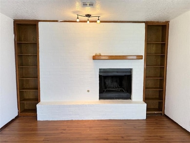 Unfurnished living room featuring a textured ceiling, wood finished floors, and a fireplace