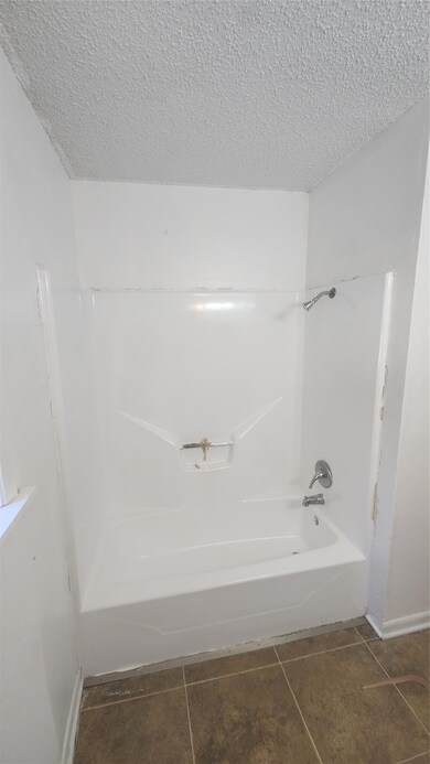 Bathroom featuring tile patterned flooring, a textured ceiling, and shower / bathtub combination