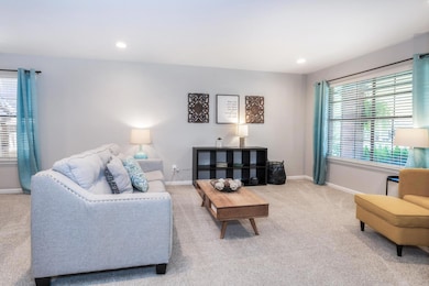 Carpeted living area featuring baseboards and recessed lighting