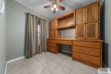 Unfurnished office with built in desk, ceiling fan, and light tile patterned floors