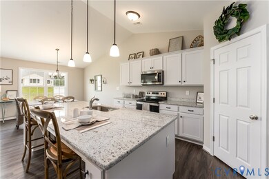 Kitchen with appliances with stainless steel finishes, pendant lighting, light stone countertops, lofted ceiling, and a breakfast bar area