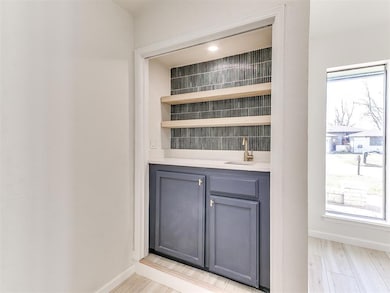Bar featuring a sink, baseboards, wet bar, and lig