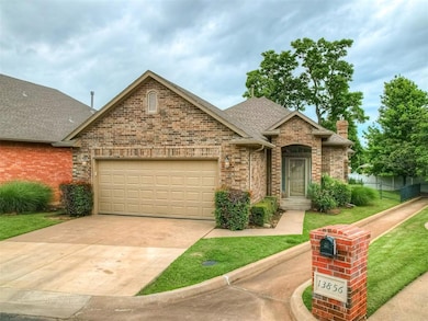 View of front of property with an attached garage, driveway, brick siding, a shingled roof, and a chimney