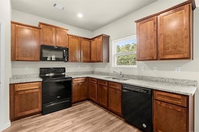 Kitchen featuring black appliances, a sink, light 