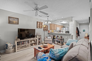 Living area with a ceiling fan, light wood-type flooring, recessed lighting, a textured ceiling, and a chandelier