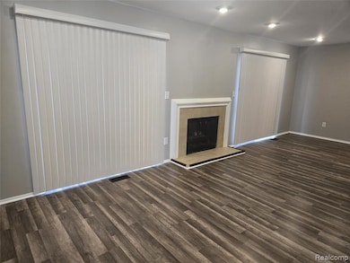 Unfurnished living room with a tile fireplace, dark wood finished floors, and recessed lighting