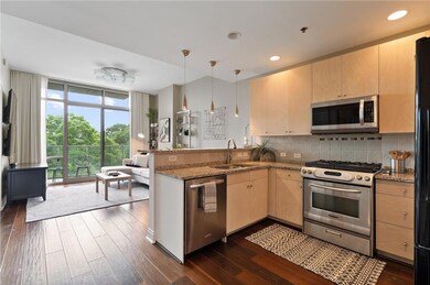 Kitchen featuring stainless steel appliances, light brown cabinets, a peninsula, backsplash, and dark wood-style floors