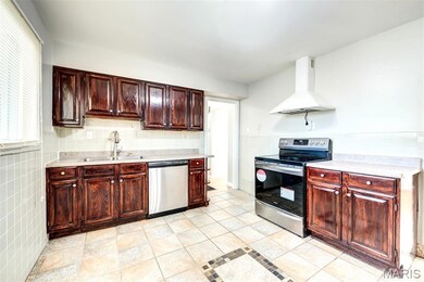 Kitchen featuring tile walls, stainless steel appliances, exhaust hood,  countertops, and light tile patterned flooring