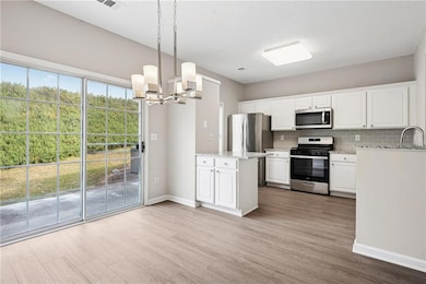 Kitchen featuring white cabinets, wood finished fl