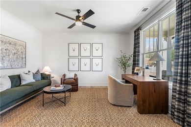 Office space with crown molding, visible vents, an