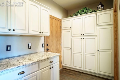 Kitchen featuring light stone counters, dark wood finished floors, and white cabinets