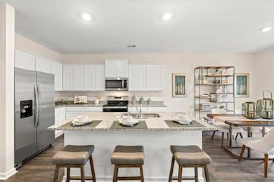 Kitchen featuring sink, stainless steel appliances, an island with sink, and white cabinets