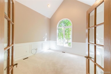 Carpeted spare room featuring a decorative wall, wainscoting, high vaulted ceiling, french doors, and recessed lighting