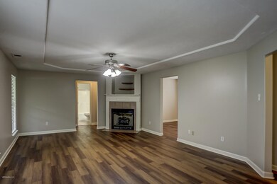 Unfurnished living room with dark wood-type flooring, a tile fireplace, and ceiling fan