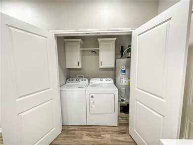 Washroom featuring cabinet space, water heater, separate washer and dryer, and light wood-type flooring