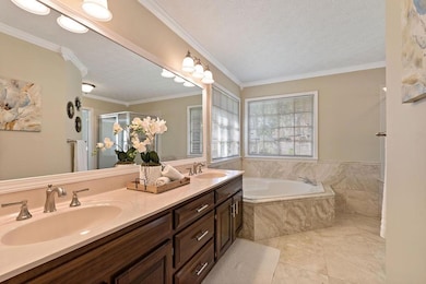 Bathroom featuring ornamental molding, double vanity, a bath, a textured ceiling, and a stall shower
