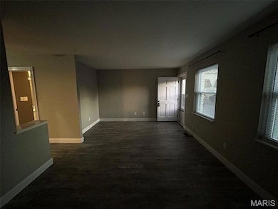 Empty room featuring baseboards and dark wood-type flooring