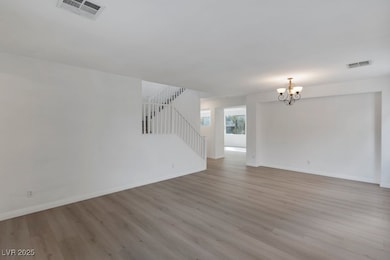 Unfurnished living room featuring light wood-style flooring, a chandelier, and stairs