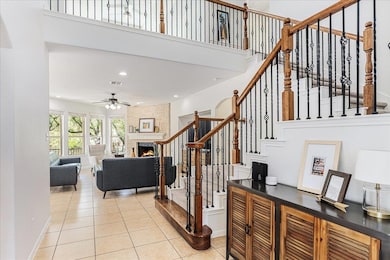 Staircase featuring ceiling fan, a fireplace, til