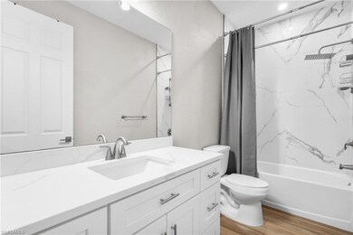 Bathroom with shower / bath combo, light wood-style flooring, and vanity