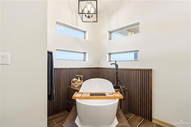 Bathroom with a freestanding tub, a chandelier, and wainscoting