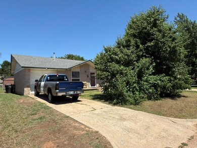 View of property exterior featuring brick siding, a garage, concrete driveway, a yard, and roof with shingles