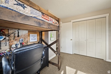 Carpeted bedroom with a textured ceiling and a closet