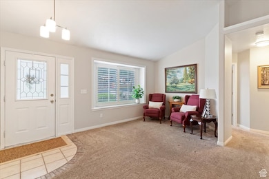 Carpeted foyer entrance with lofted ceiling, tile patterned flooring, and a chandelier